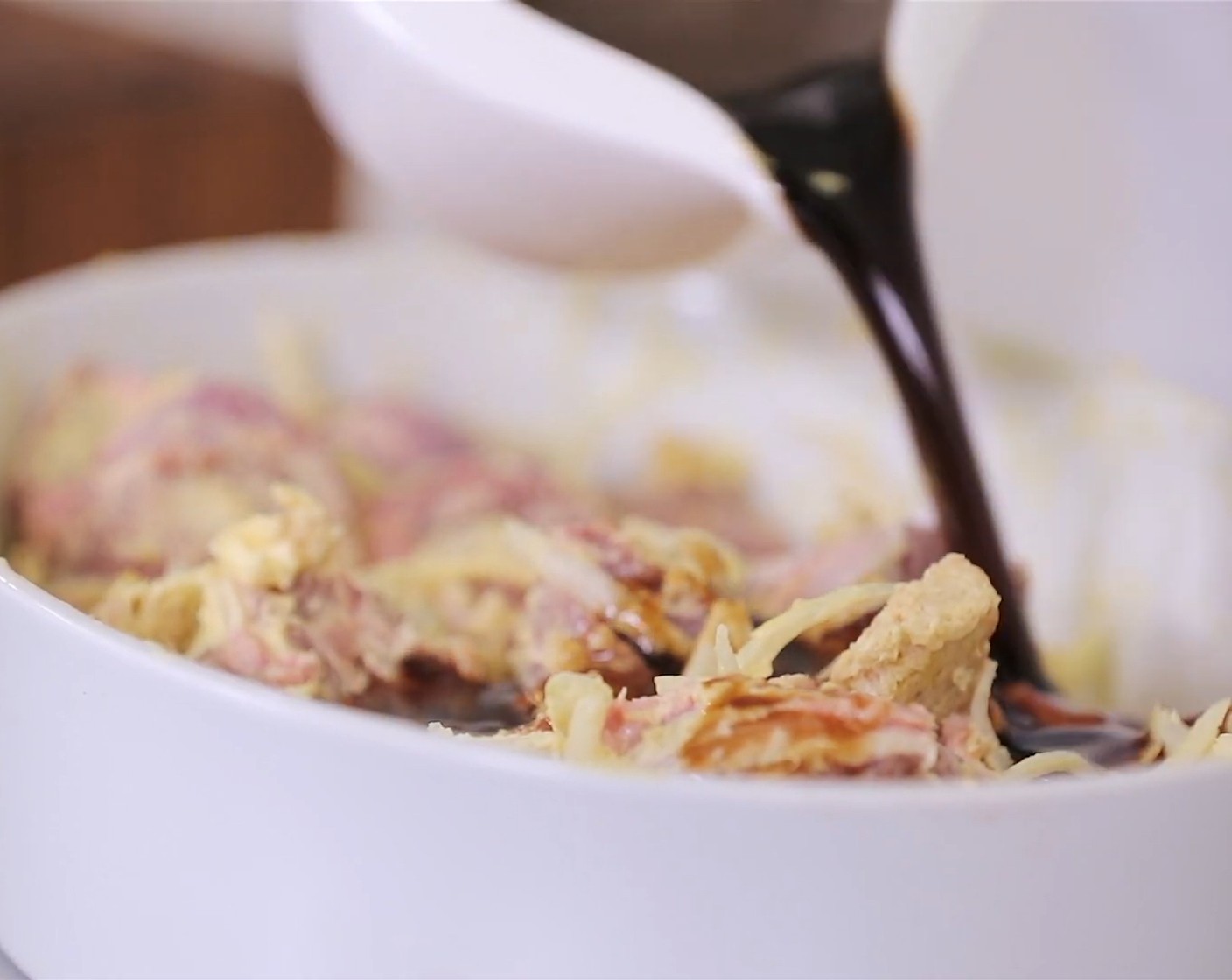 Schritt 3 Als nächstes alle Zutaten in folgender Reihenfolge in die Porzellanschale geben: Zwiebeln, Knoblauch, Thymian (2 Zweige), Lorbeerblätter (2), Schweinebacken (1 kg), Butter (75 g) in Scheiben geschnitten, das Olivenöl, Brot, Salz (wenig) und Pfeffer (wenig). Das Ganze mit dem Fond übergiessen und anschliessend die Porzellanform auf den Gitterrost in den vorgeheizten Ofen zum Garen schieben.