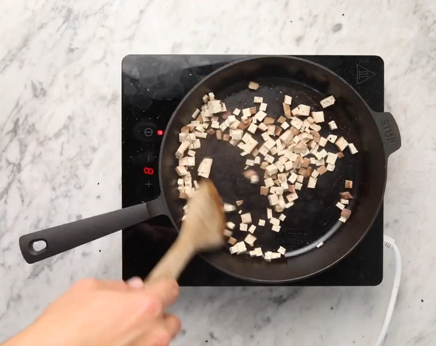 Schritt 1 Den Tofu (80 g) in kleine Würfel schneiden und in einer Bratpfanne bei mittlerer Hitze ohne Öl ca. 5-7 Minuten knusprig braten. Anschliessend beiseitestellen.