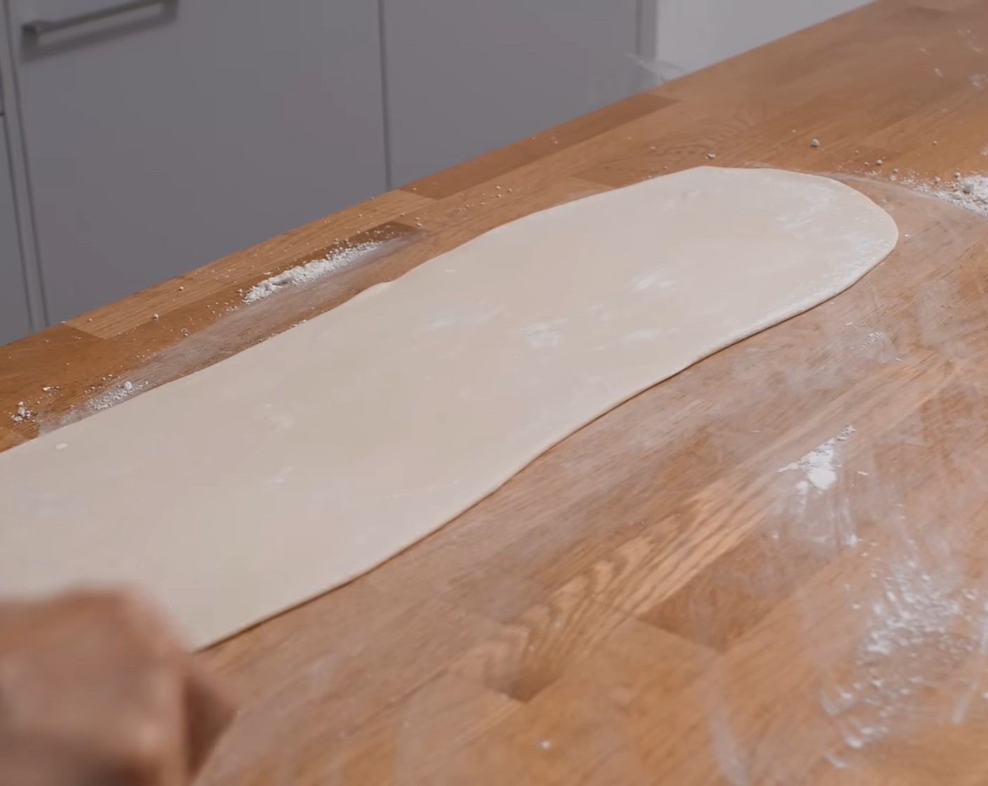 Schritt 6 Anschliessend den Teig auf der langen Seite vorsichtig links und rechts – von der Mitte nach – in die Breite ziehen und weiter ausrollen. Der Teig sollte so dünn sein, dass man «dadurch Zeitung lesen könnte».