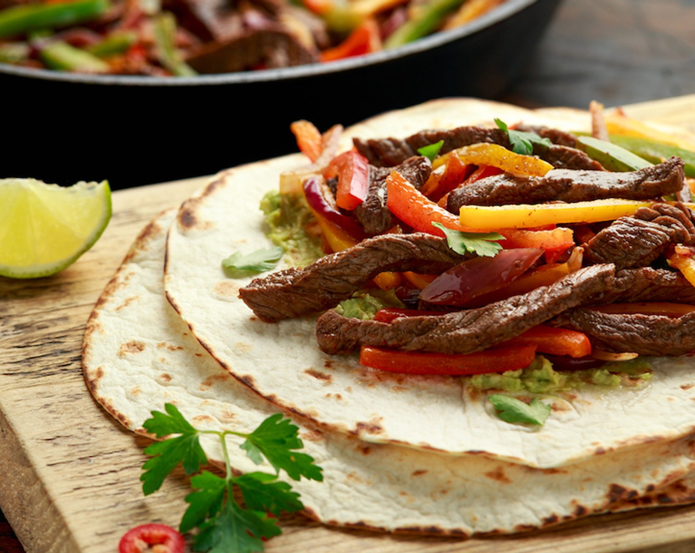 Schritt 11 Als nächstes die Tortilla aus dem Garbehälter nehmen und auf die Teller legen. ¼ der Füllung längs in der Mitte verteilen, die Crème Fraîche (90 g) und den Käse (1 EL) nach Belieben auf die Füllung verteilen, aufrollen und sofort servieren.