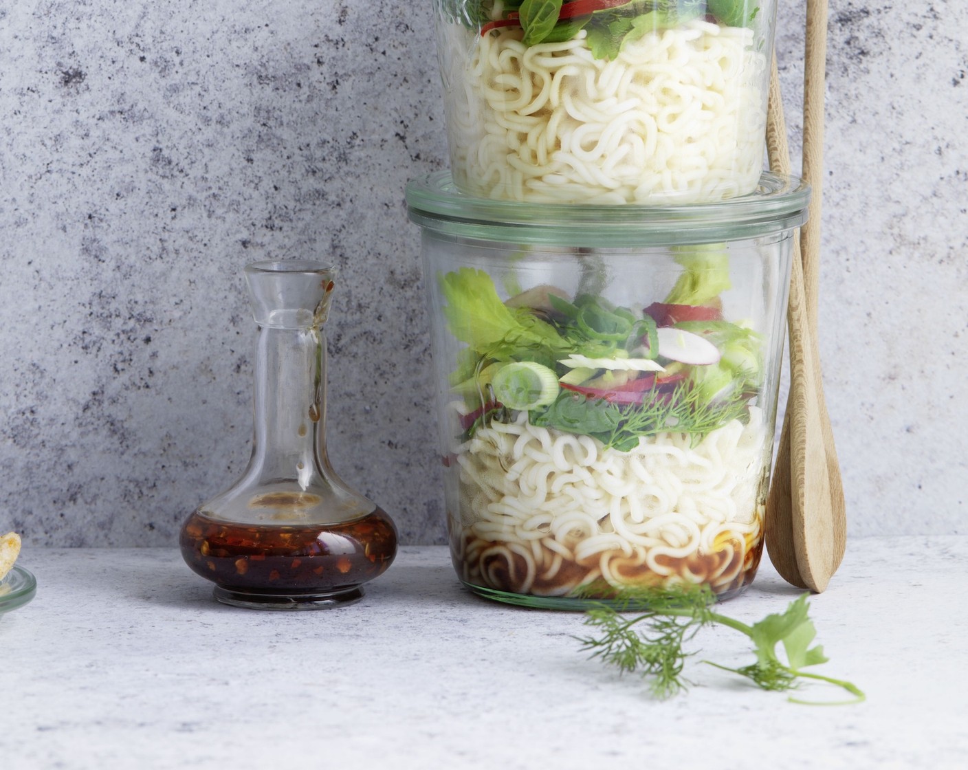 Schritt 3 Peperoni (1) halbieren und entkernen. Anschliessend Peperoni, Radieschen (4), Frühlingszwiebeln (2), Sellerie (2 Stangen) und Champignons (150 g) in feine Scheiben schneiden und in eine Schüssel geben. Kräuter (1 Bd.) grob hacken und unter das Gemüse mischen. Den Kräuter-Gemüse-Mix auf die Nudeln verteilen und die Sauce darübergiessen. Gläser verschliessen, gut schütteln, dann ist der Salat essbereit.