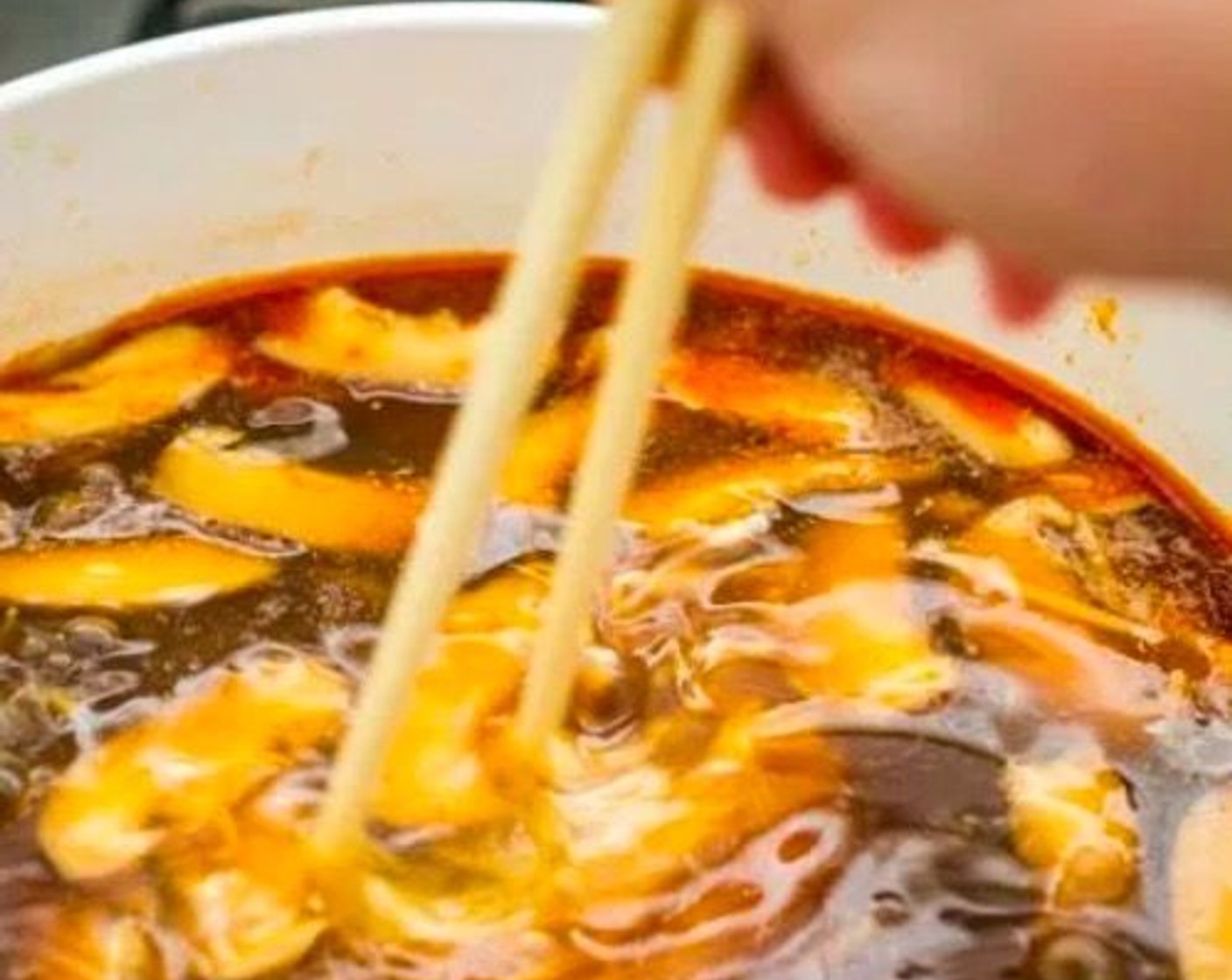 Schritt 9 Eier (2) in einem langsamen, gleichmässigen Strahl in die Suppe giessen. Während die Eier in die Suppe gegossen werden, mit den Stäbchen umrühren, um eine dünne, seidige Eierkonsistenz zu erhalten, oder langsam schwenken, um eine stückigere Textur zu erhalten.