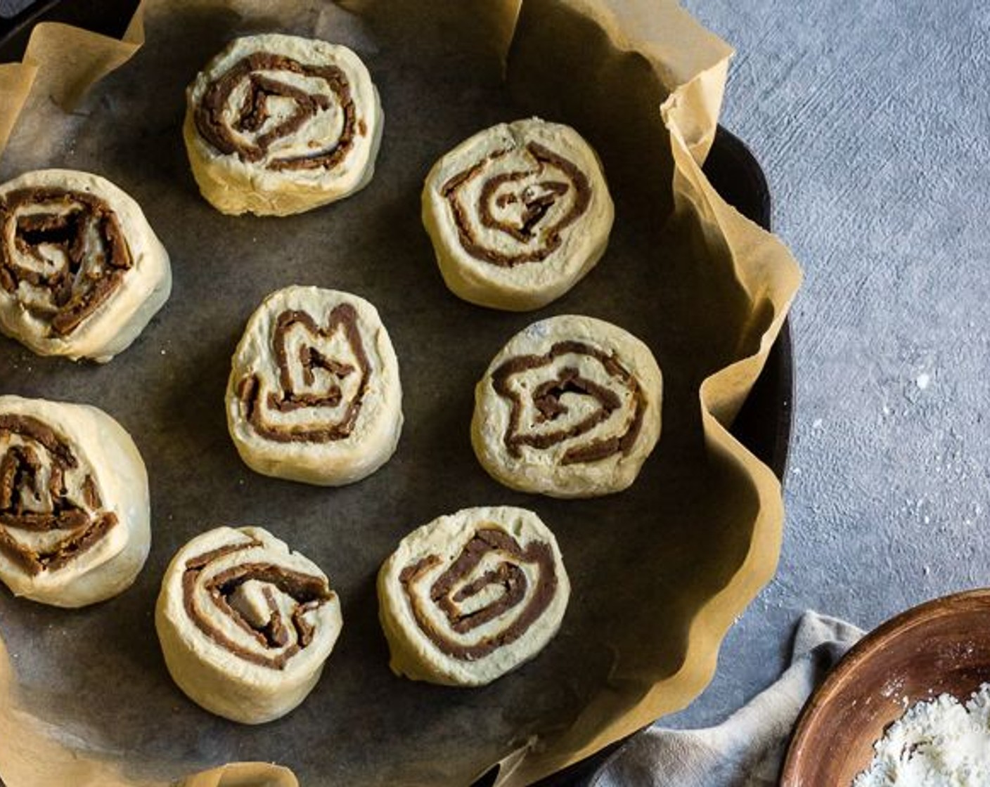 Schritt 12 Brötchen mit einem 30 cm langen Stück ungewürzter Zahnseide in acht Stücke schneiden; Zahnseide unter den ausgerollten Teig legen. Danach die Zahnseide um den Teig herum legen und oben kreuzen, und den Teig schneiden. Wiederholen mit dem übrigen Teig. Die Stücke auf die mit Backpapier ausgelegte Pfanne legen.