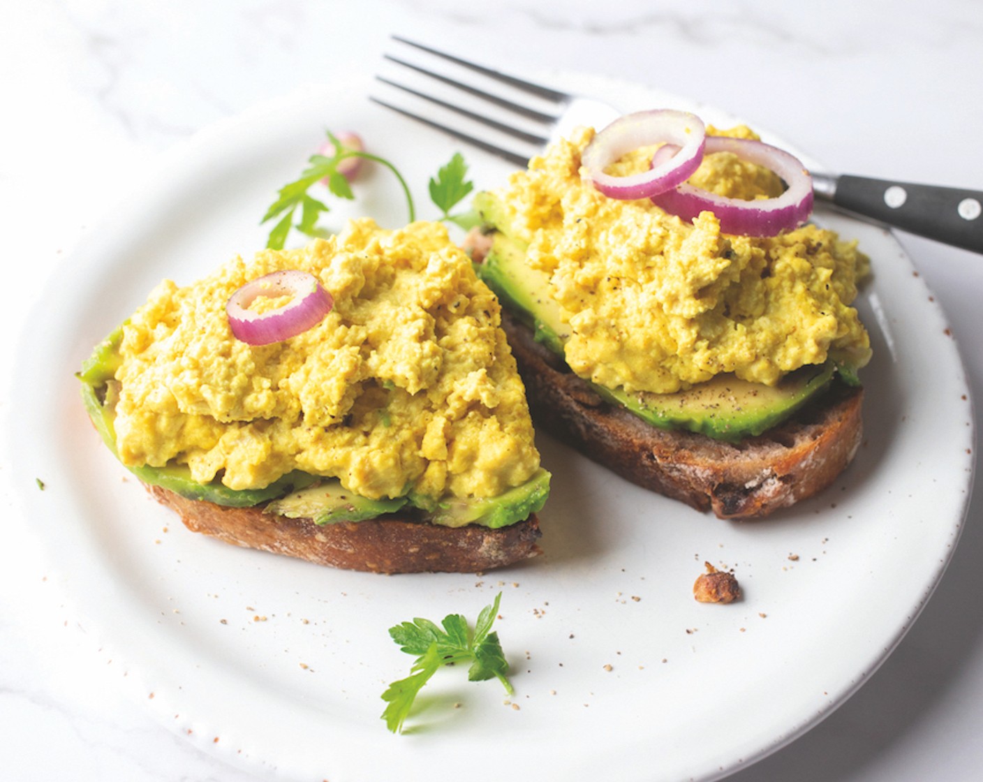 Schritt 3 Das Brot (1 Scheibe) nach Belieben toasten und mit den Avocadoscheiben (1/2) belegen. Den Rühr-Tofu darauf verteilen und geniessen.