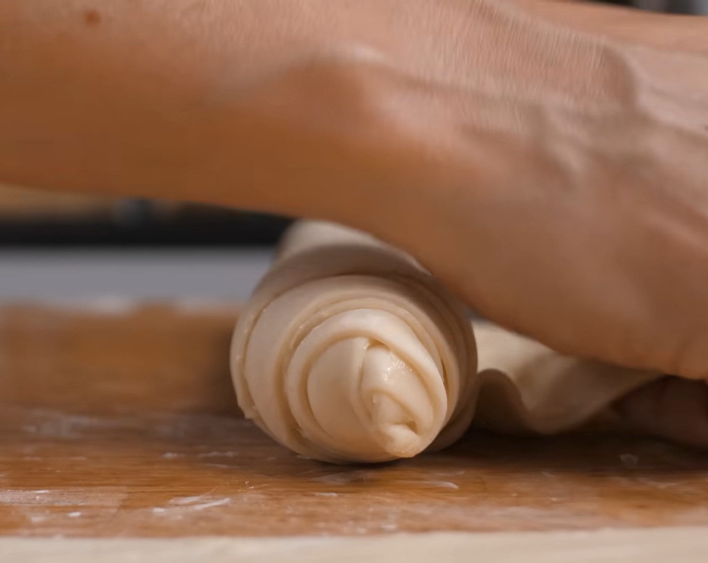 Schritt 10 Danach einen bestrichenen Teigstreifen von der schmalen Seite satt zu einer Rolle aufrollen. Dabei den Teig links und rechts immer wieder etwas breit ziehen.