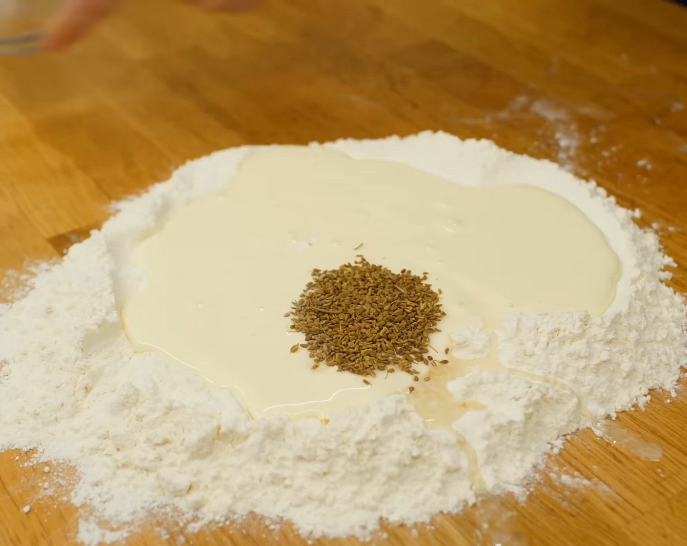 Schritt 3 Danach das Mehl (220 g) auf die Arbeitsfläche geben, in der Mitte eine Mulde formen und die Eiermischung in die Mulde geben.