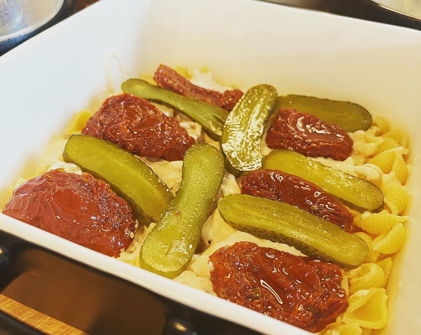 Schritt 5 Jetzt wird das Ganze in einer Gratinform fertiggestellt. Zuerst die Pasta hineingeben und mit der Hälfte der Sauce bedecken. Dann Gurken und Tomaten (6) darauf verteilen.