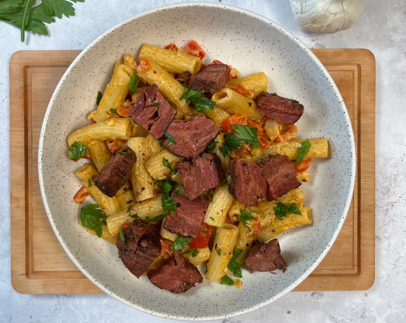 Schritt 5 Die Nudeln mit der Sauce und dem veganen Parmesan (1 1/3 Esslöffel) vermischen. Das Steak in Würfel schneiden und über die Nudeln geben. Mit Salz (wenig) und Pfeffer (wenig) würzen und mit Petersilie (wenig) garnieren.