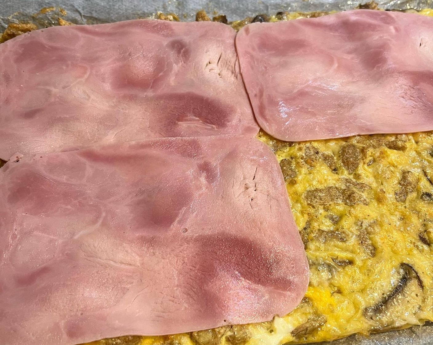 Schritt 4 Backblech aus dem Ofen nehmen, Schinken (4 Scheiben) und übrigen Käse darauf verteilen.