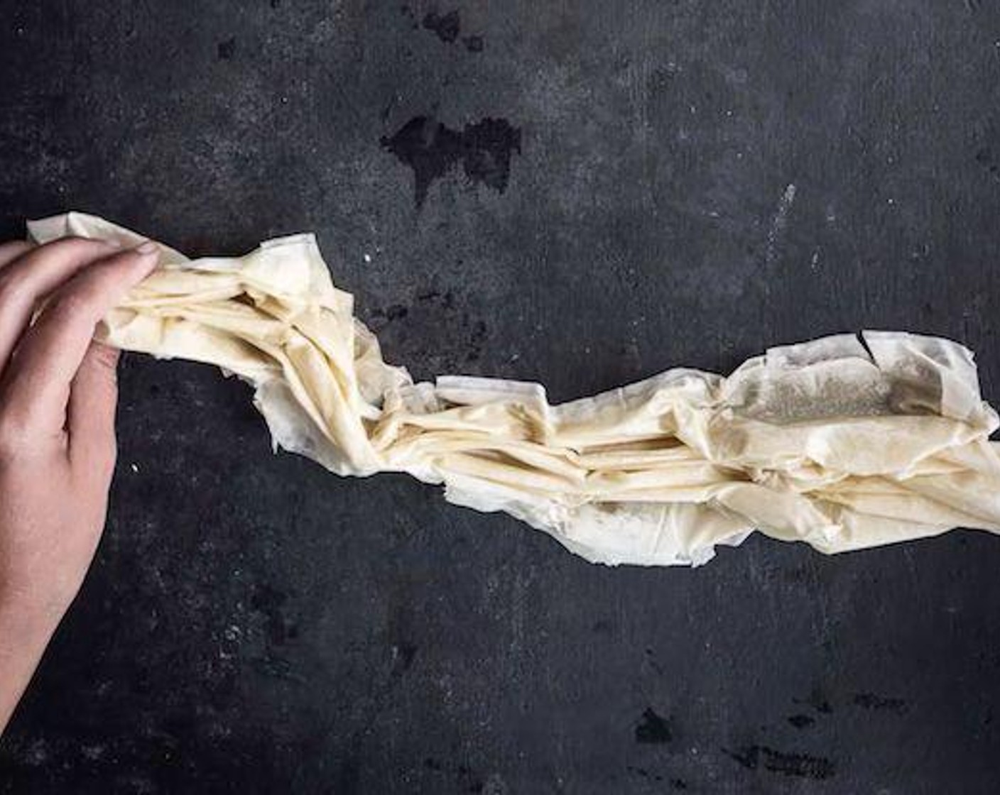 Schritt 4 Mit den Fingern den Fillo in Längsrichtung zu einem lockeren, gekräuselten Streifen zusammenknautschen; es ist in Ordnung, wenn der Phyllo etwas reisst. Den Teig zu einer lockeren, gekräuselten Spirale aufwickeln, in die vorbereitete Form legen und mit dem restlichen Phyllo-Teig wiederholen, bis die Form gefüllt ist. Je nach Grösse des Phylloteigs sollte man 5-7 Spiralen erhalten.