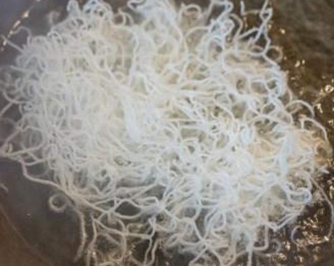 Schritt 3 Trockene Reisnudeln (240 ml) frittieren. Es sollte nur ein paar Sekunden dauern, bis sie sich aufblähen. Mit einem Sieb herausnehmen. Beiseite stellen.