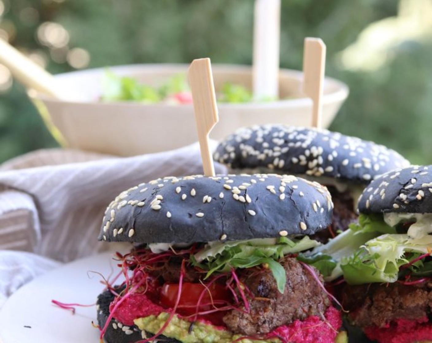 Schritt 11 Die Burger werden in folgender Reihenfolge zusammengesetzt: auf die untere Hälfte des Brötchens das Avocadopüree streichen, gefolgt von dem Rote-Bete-Hummus, einigen Salatblättern und dem Burger Patty. Zum Schluss mit den Rote-Bete-Sprossen toppen. Die obere Brötchenhälfte mit Tsatsiki bestreichen und auf den Burger legen. Sofort servieren und geniessen.