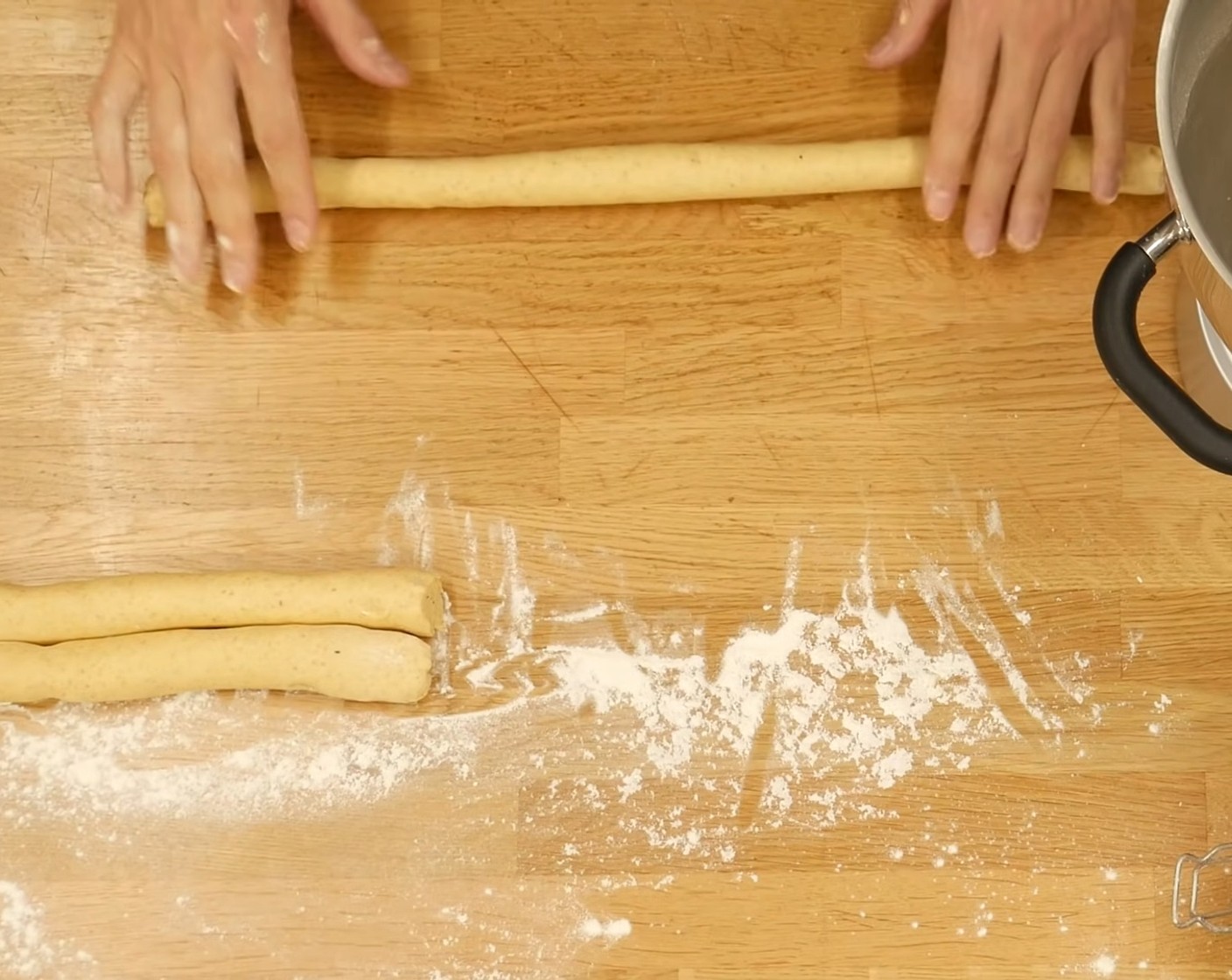 Schritt 4 Den Teig auf eine leicht bemehlte Arbeitsfläche geben und halbieren. Aus jedem Teigstück einen Strang mit etwa 3 cm Durchmesser rollen und halbieren. Diese Teigrollen in ein Teigtuch oder Frischhaltefolie einpacken und für mindestens 1 Stunde (oder über Nacht) kühlstellen.