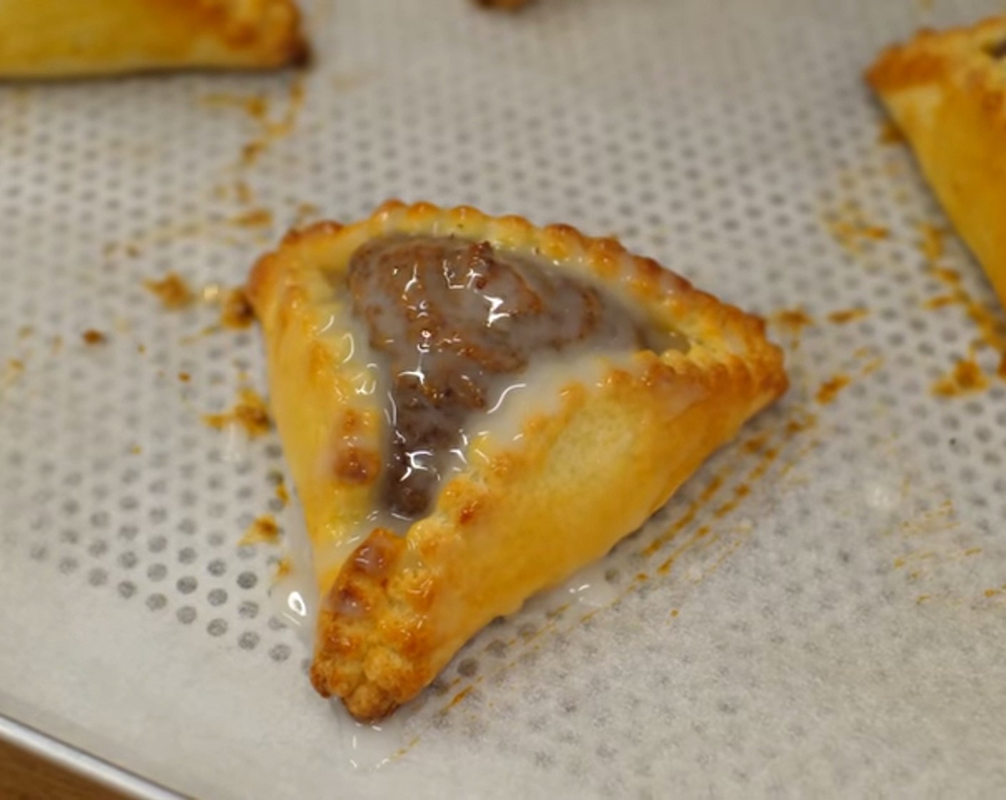 Schritt 14 Während die Pfaffenhüte im Ofen backen, etwas Zitronensaft (1/2) zum Puderzucker (50 g) geben und gut durchmischen. Soviel Zitronensaft verwenden, bis das Ganze streichfähig wird. Nach dem Backen, die Pfaffenhüte – vor allem die Füllung - gleichmässig mit diesem Zuckerguss bestreichen.