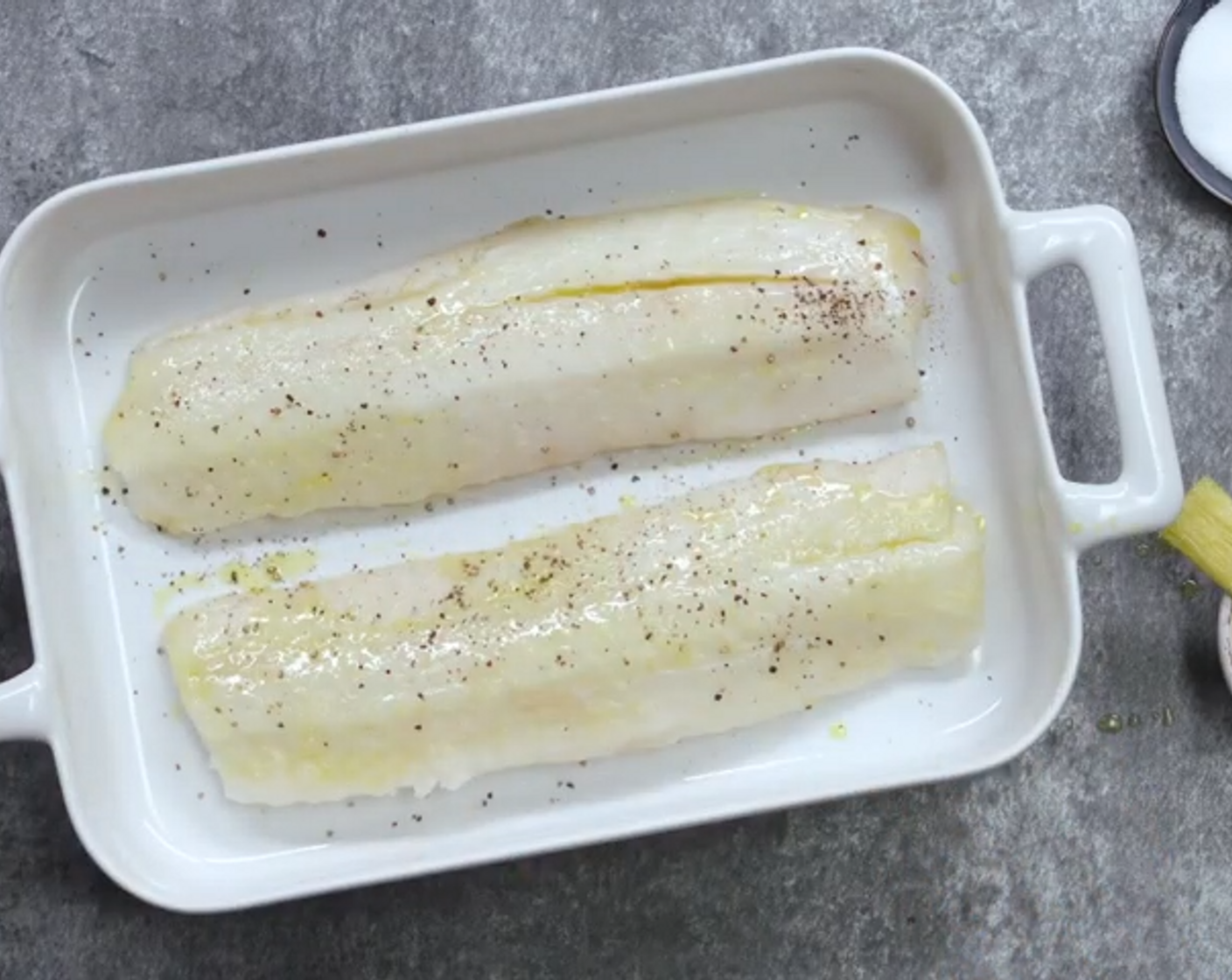 Schritt 2 Kabeljaufilets (600 g) von beiden Seiten mit Salz (wenig) und Pfeffer (wenig) würzen. Mit der Hälfte des Olivenöl (90 ml) rundum bestreichen und in eine Auflaufform legen.