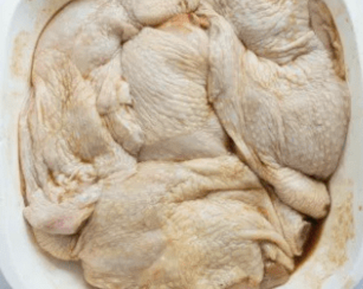 Schritt 2 Die Marinade über die Hähnchenschenkel (4 Stück) verteilen und sanft in das Hähnchen einmassieren.