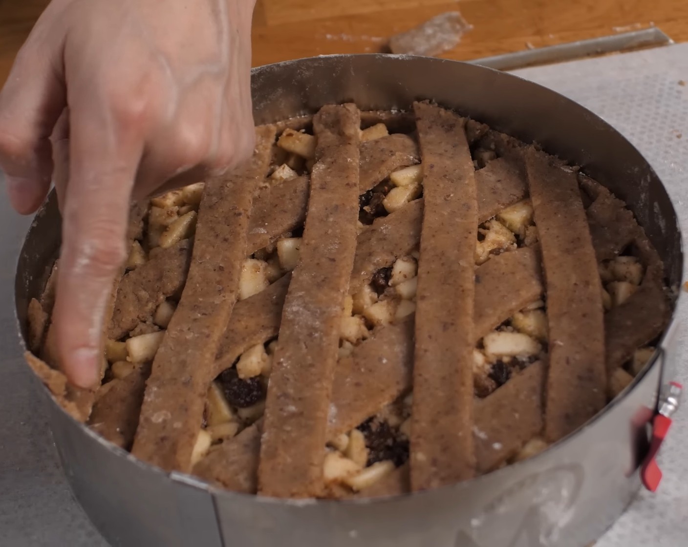 Schritt 17 Die Streifen als Gitter auf den Kuchen legen. Dabei zwischen den einzelnen Streifen jeweils einen Abstand von zirka 2 cm lassen.  Anschliessend den überschüssigen Teig vom Kuchenrand abschneiden oder während dem Auflegen mit den Fingern abdrücken.