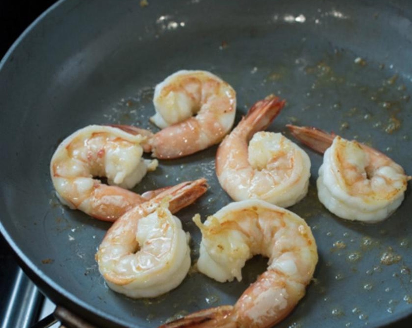 Schritt 5 Separate Pfanne erhitzen, 2 Esslöffel Knoblauchöl in die Pfanne geben und die Shrimps (12) portionsweise darin braten. Shrimps beiseite stellen, wenn sie vollständig gar sind.