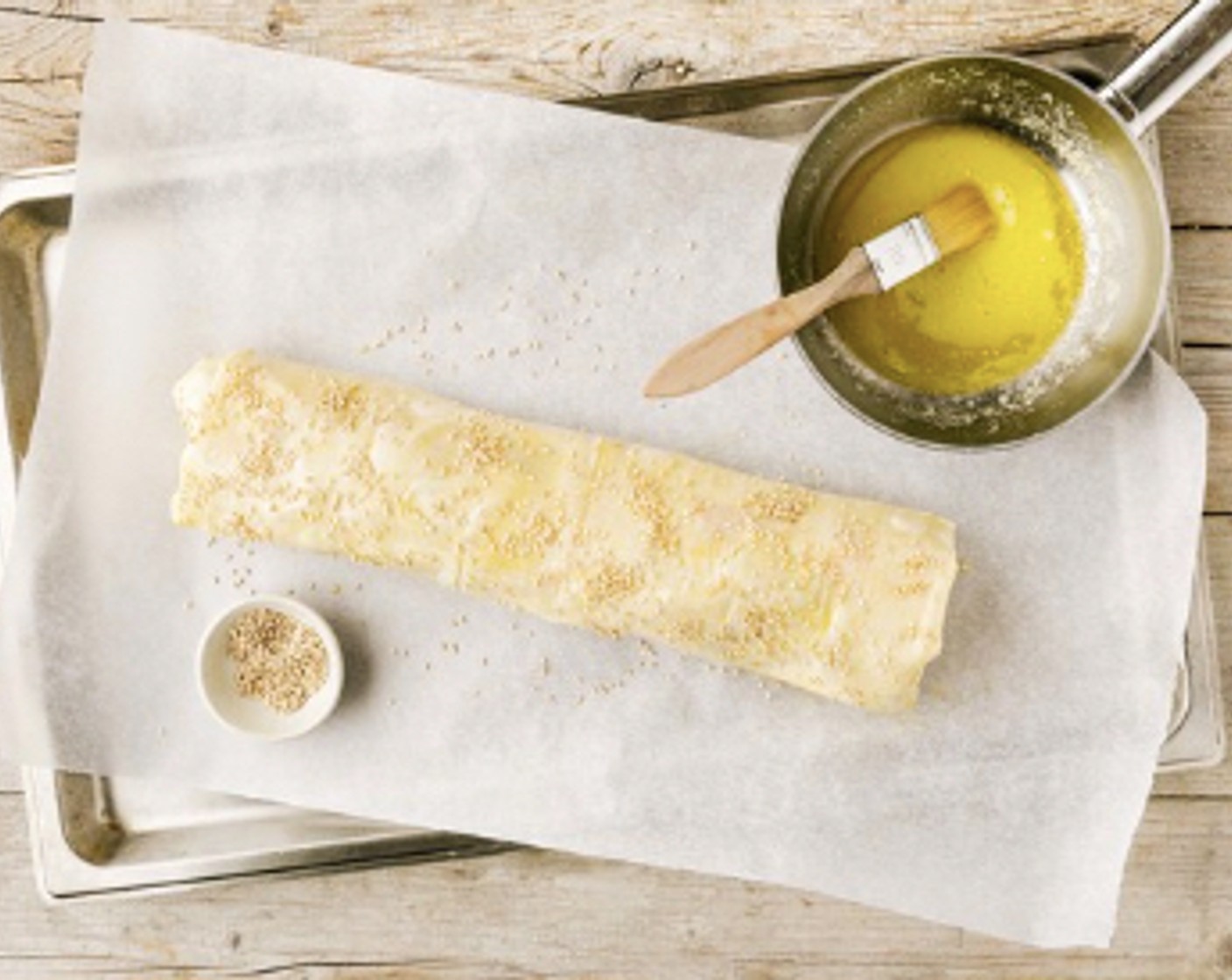 Schritt 5 Rundum mit Butter (3 1/3 Esslöffel) bestreichen und mit Sesam (2 Esslöffel) bestreuen. 20 bis 25 Minuten in der Mitte des vorgeheizten Ofens bei 200 °C Ober-/Unterhitze backen.