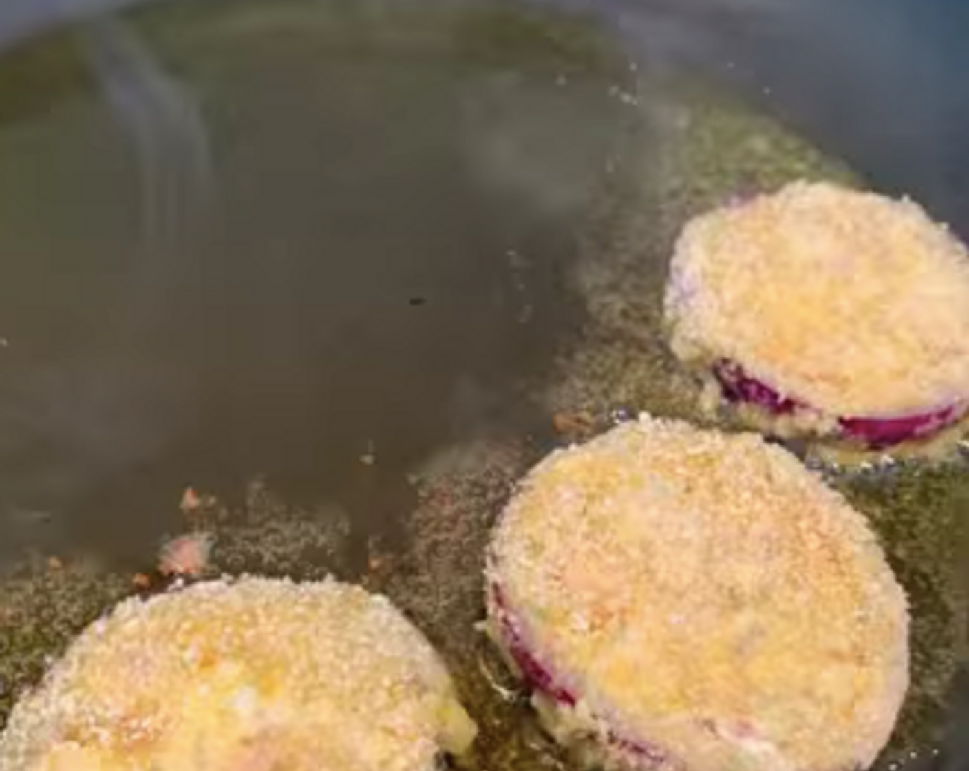 Schritt 5 Eine Bratpfanne mit Rapsöl (nach Bedarf) bei mittlerer Hitze erwärmen und die Zwiebel-Taler nacheinander für wenige Minuten von beiden Seiten goldbraun braten. Die Ringe zuerst auf ein Küchenpapier legen und abtropfen lassen. Dann zurück auf das Blech legen und im Ofen bei 80 °C warmhalten.