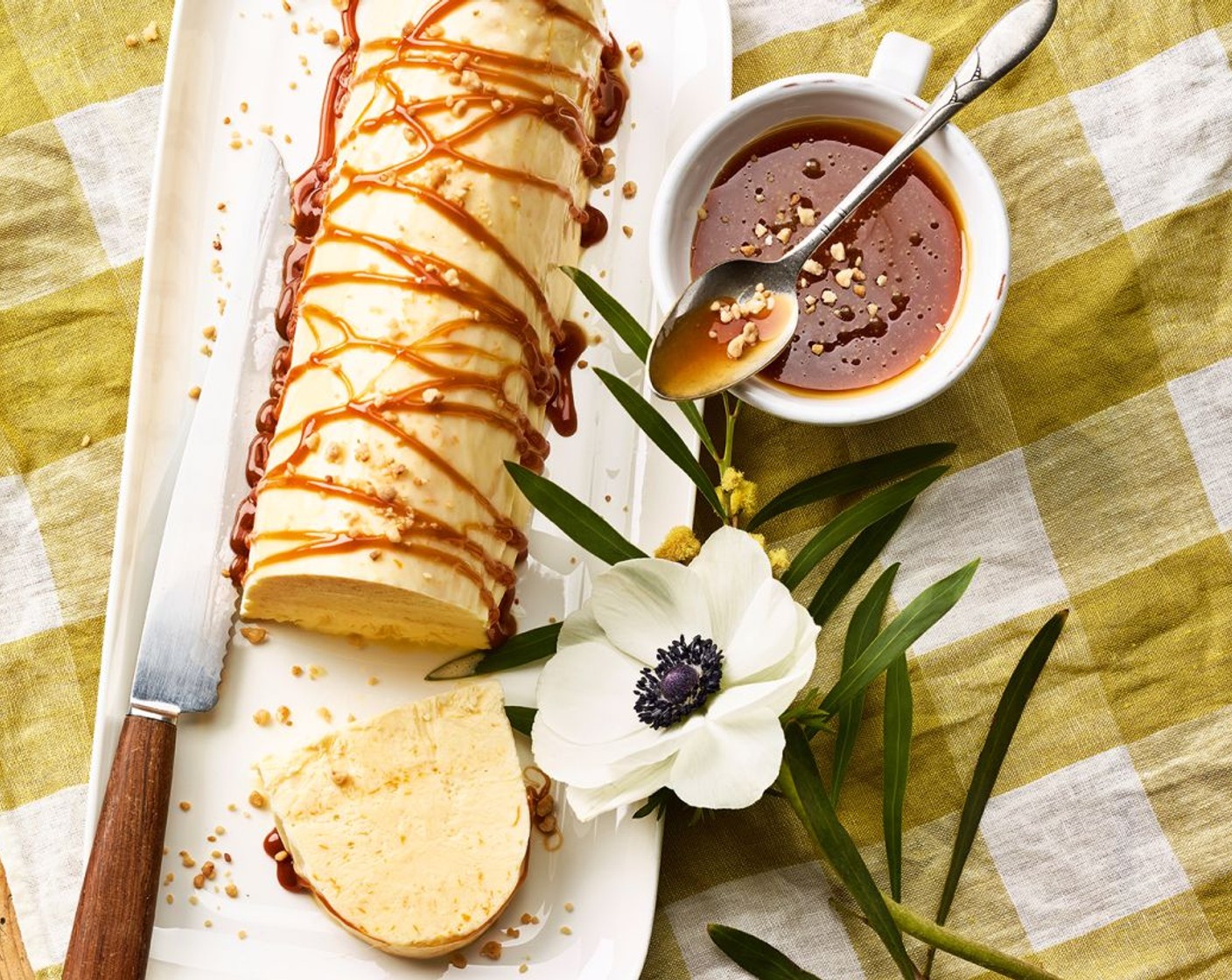 Schritt 5 Die Parfaitform nur ganz kurz in heisses Wasser stellen, dann die Sauerrahm-Orangen- Glace auf eine Platte stürzen und die Klarsichtfolie abziehen. Zum Servieren das Parfait mit der warmen Caramelsauce übergiessen. Nach Belieben mit Mandelkrokant oder Mandelblättchen garnieren.