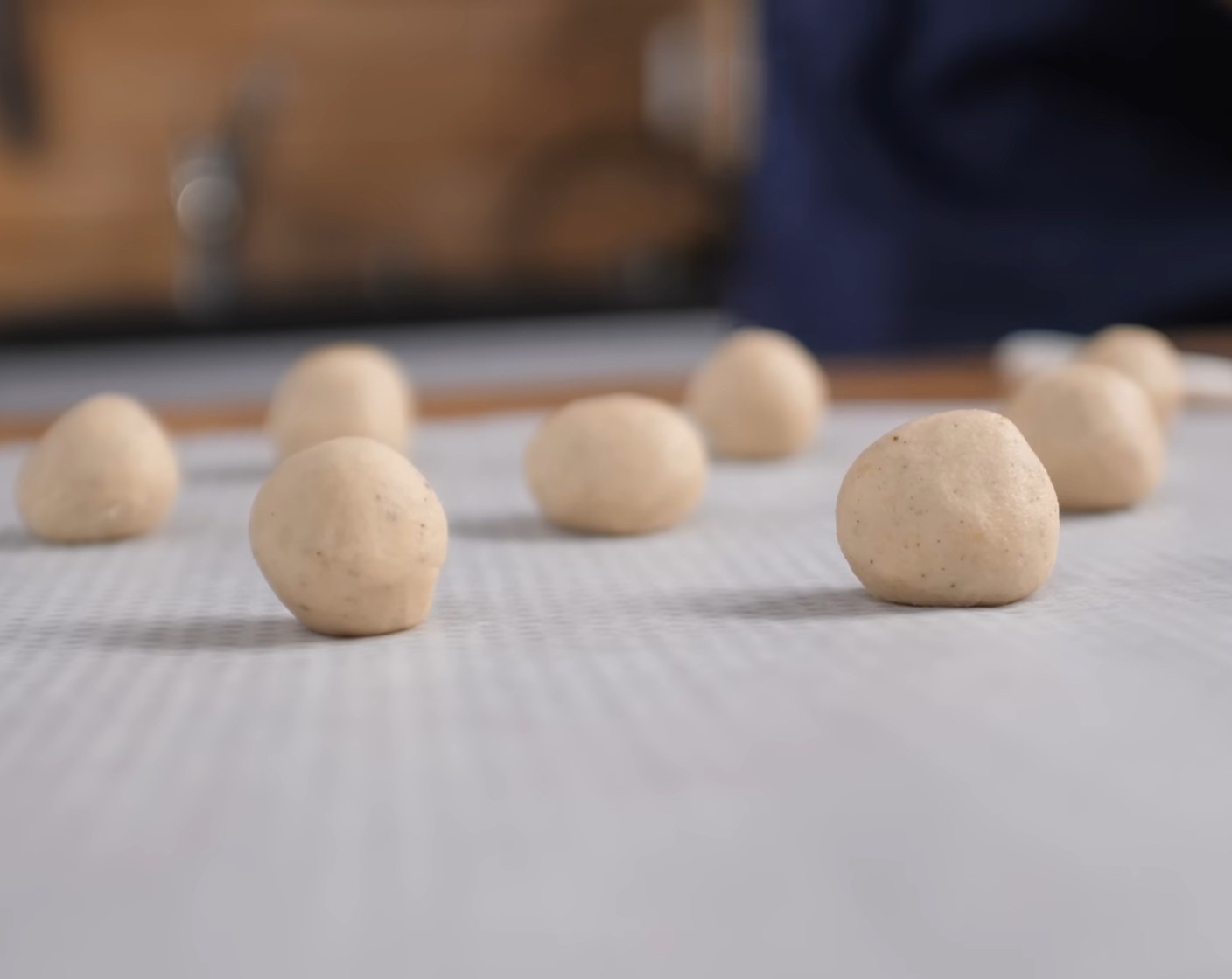 Schritt 4 Aus den Teigstücken gleichmässige Kugeln formen, auf ein mit Backpapier belegtes Blech legen und leicht flach drücken.