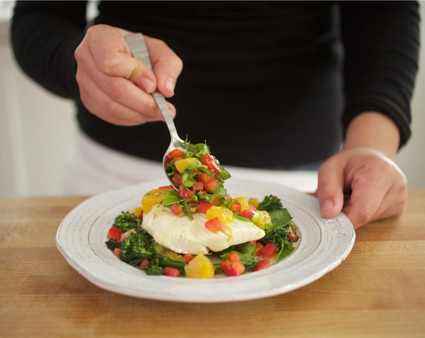 Schritt 12 Den Broccolini gleichmässig in der Mitte von zwei Tellern verteilen. Anschliessend das Fischfilets auf den Broccolini legen. Basilikum- und Paprikasauce über den Fisch löffeln. Vinaigrette darüberträufeln.