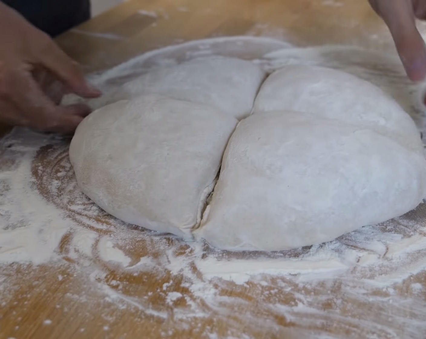 Schritt 8 Nach 2 Stunden die Teigoberfläche gut mit Mehl bestäuben und den Teig etwas im Mehl drehen, damit er nicht an der Arbeitsplatte klebt. Anschliessend mit einem dünnen Rollstab den Teig - zuerst von links nach recht und dann von oben nach unten - tief zu einem Kreuz eindrücken. Hinweis: Teigstücke richtig tief abdrücken, ansonsten besteht die Gefahr, dass die Brote zu fest aufreissen und das Kreuz nach dem Backen nicht mehr zu sehen ist. Es ist auch nicht schlimm, wenn der Teig fast durchgedrückt wird.