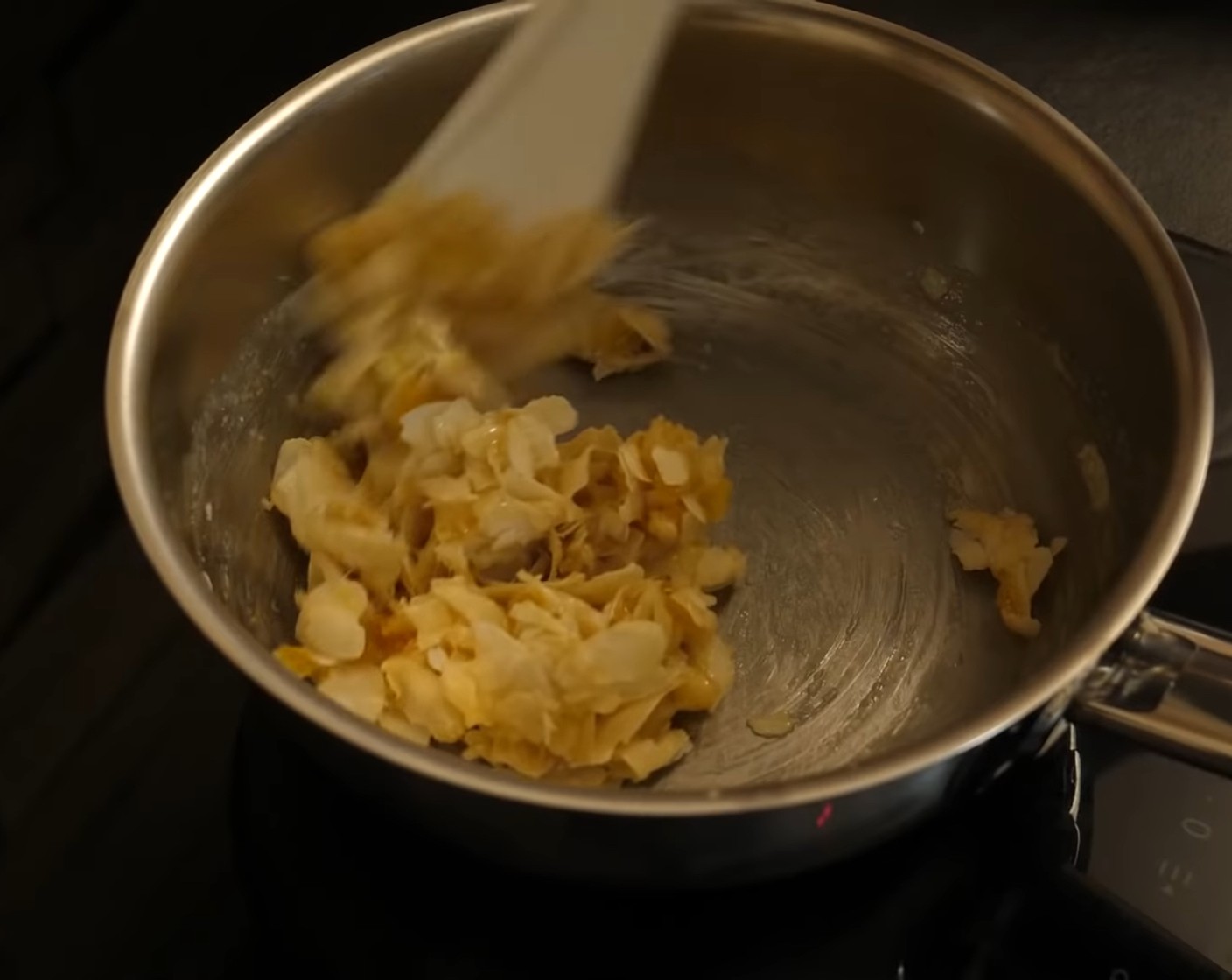 Schritt 3 Danach die Temperatur auf die kleinste Stufe stellen, das Orangeat mit den gehobelten Mandeln zur Masse geben und alles gut mischen.