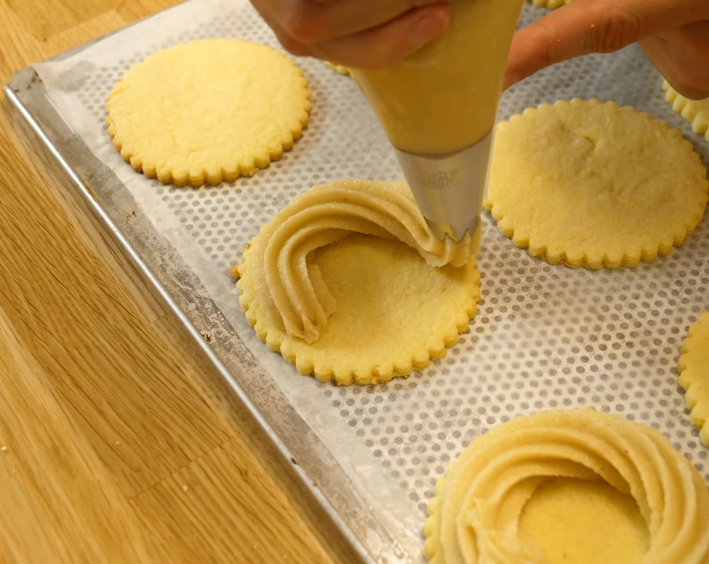 Schritt 7 Danach die Makronenmasse in einen Spritzbeutel mit 15 mm Sterntülle geben. Mit der Makronenmasse einen kleine Kranz auf die ausgekühlten Mürbeteigböden spritzen, dabei einen äusseren Rand von ca. 5 mm frei lassen. Danach die Vogelnestli über Nacht bei Raumtemperatur abstehen lassen.