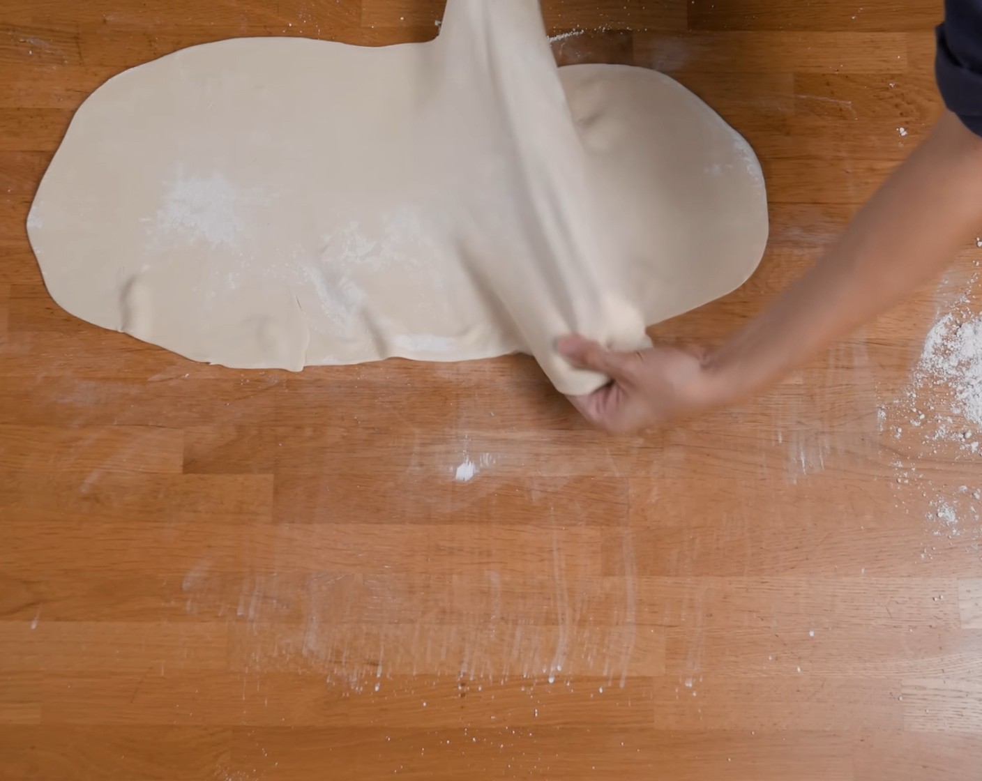 Schritt 7 Den Teig nochmals schonend von der Mitte aus in die Breite ziehen, damit er eine Breite von etwa 40 cm erreicht.