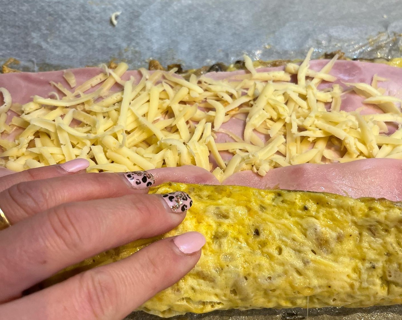 Schritt 5 Das Ganze mithilfe des Backpapiers einrollen, nochmals für 8 Minuten bei 180 °C mit Umluft im Ofen backen.