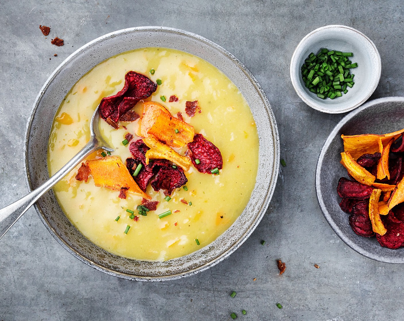 Schritt 5 Den Schnittlauch (1/2 Bd.) in Röllchen schneiden. Die Suppe in tiefen Tellern oder Suppenschalen anrichten und mit dem Schnittlauch sowie dem Speck und den Gemüsechips (2 Esslöffel) anrichten.