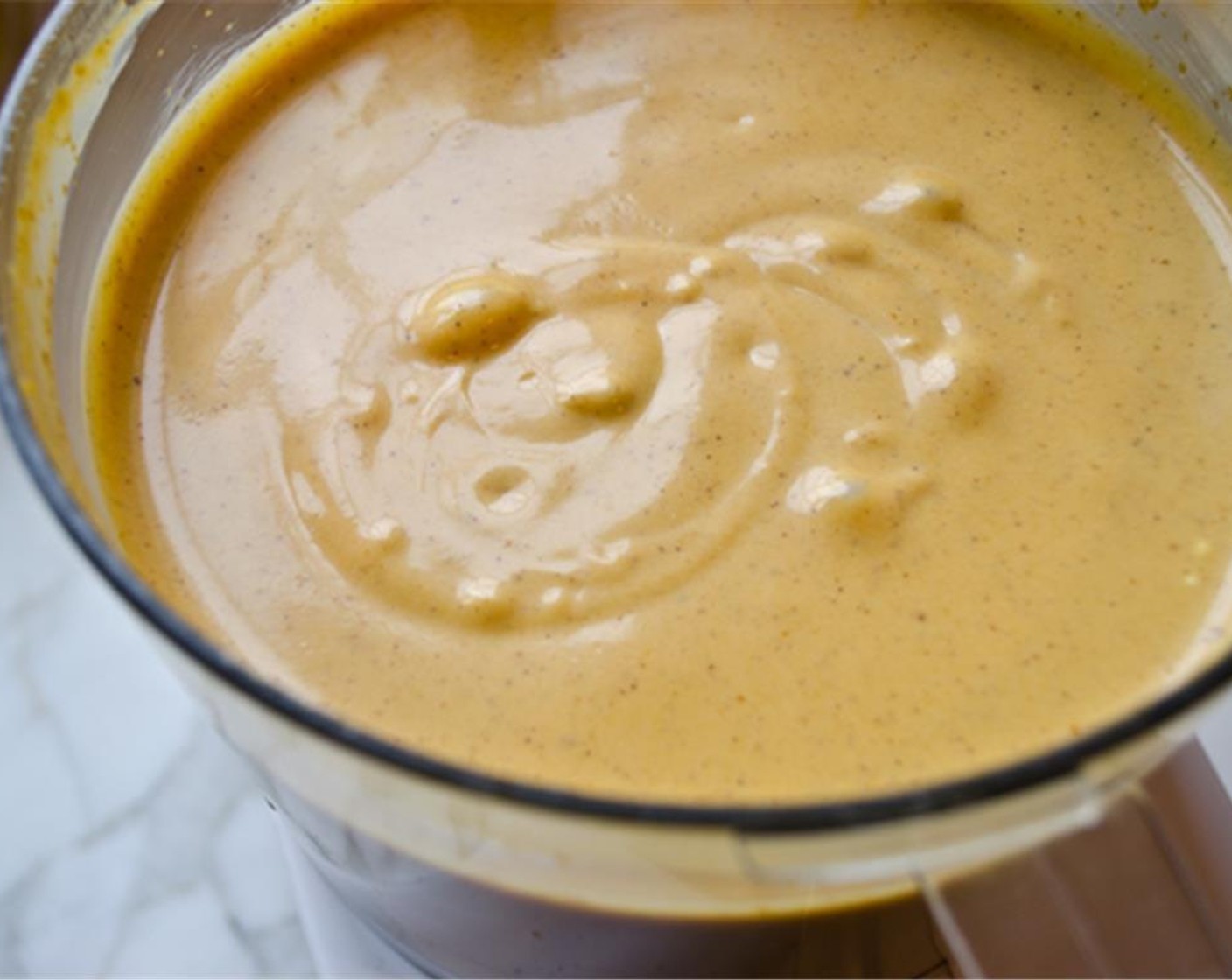 Schritt 7 Während der Verarbeitung Vollrahm (120 ml) hinzufügen. Dann den Frischkäse (680 g) in Stücke schneiden und in die Küchenmaschine geben. Etwa 30 Sekunden lang pürieren, dabei bei Bedarf die Seiten abkratzen.