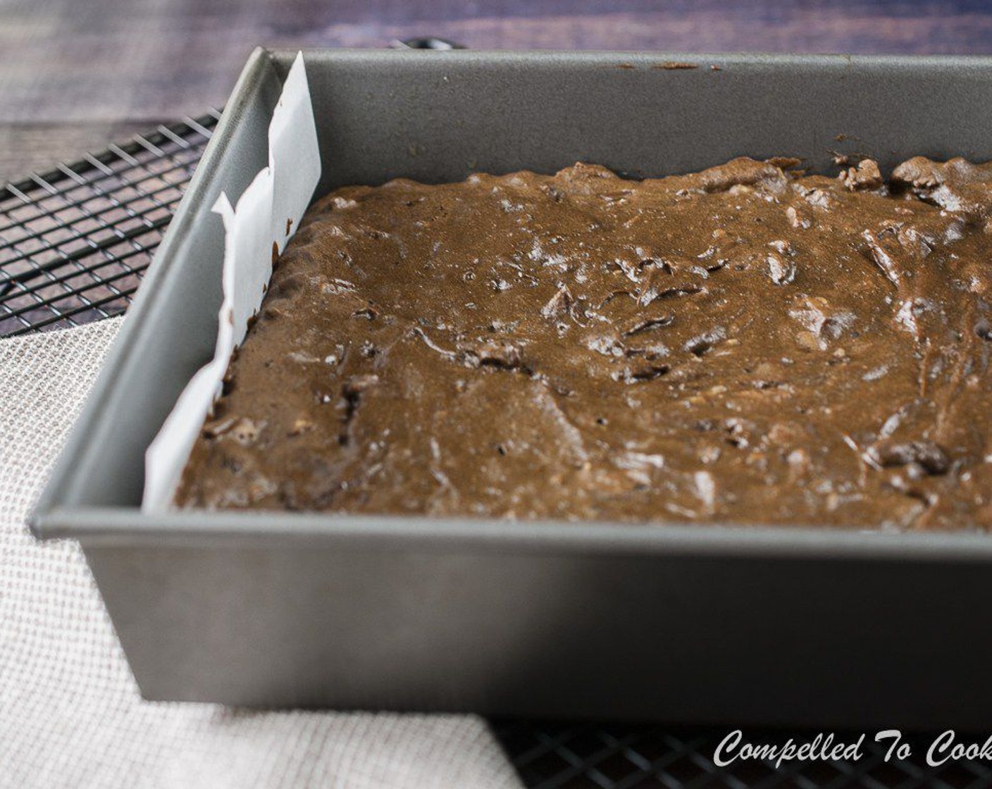 Schritt 8 18–20 Minuten backen, bis die Mitte gerade fest ist. Aus dem Ofen nehmen und auf einem Gitterrost abkühlen lassen. Am überhängenden Backpapier aus der Form nehmen und auf ein Schneidebrett legen.