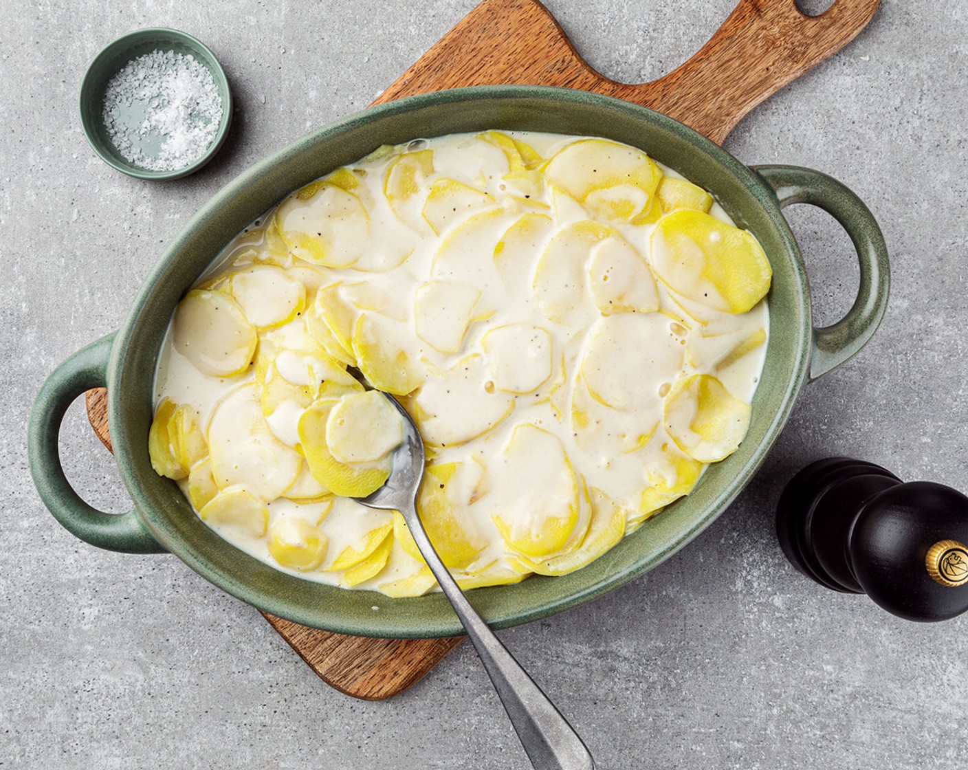 Schritt 4 In der Zwischenzeit die Gratinform mit der Butter (wenig) ausfetten. Anschliessend die Kartoffelscheiben fächerartig in der Gratinform verteilen. Die Milch-Rahm-Mischung über die Kartoffeln giessen.