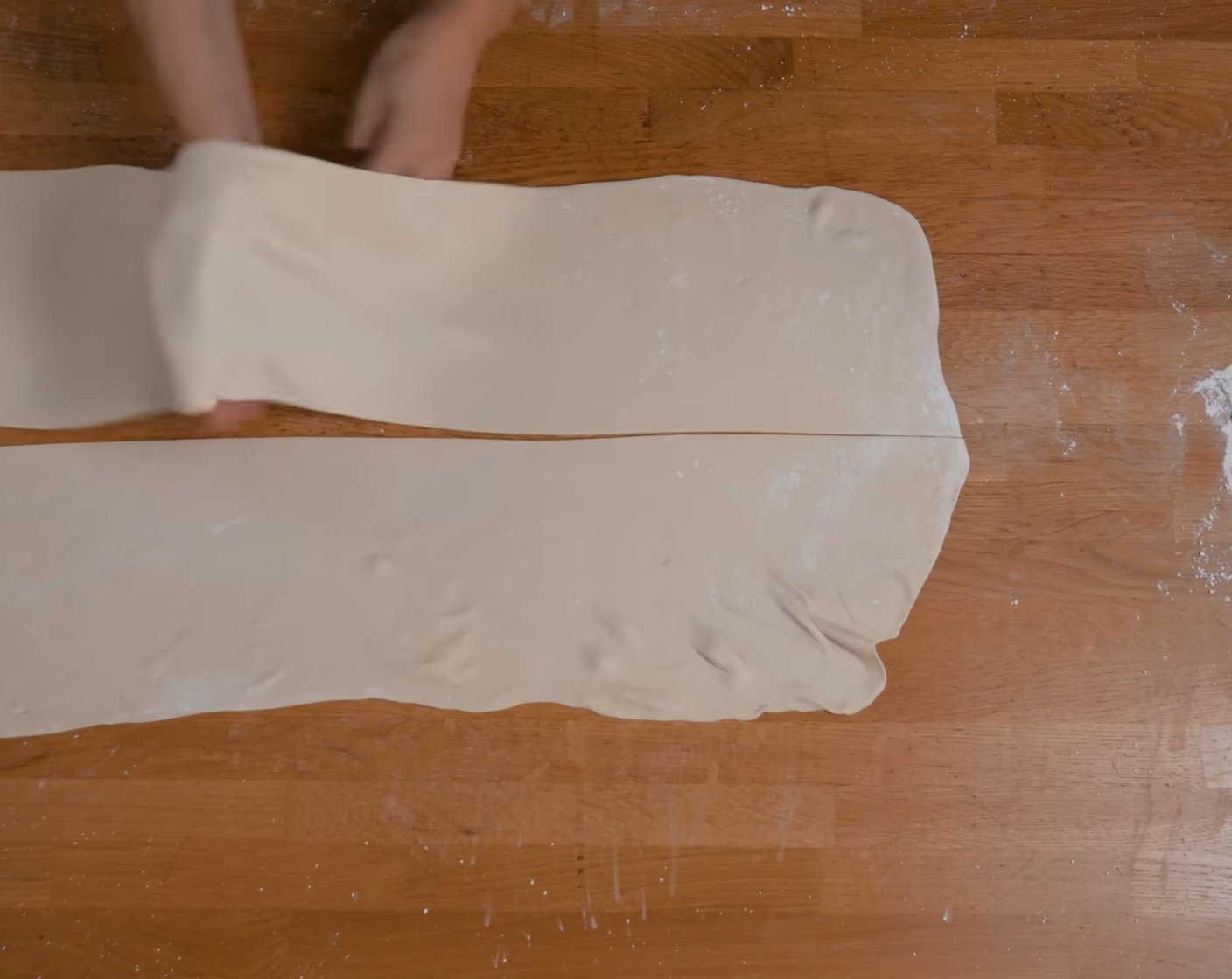Schritt 8 Anschliessend den Teig der Länge nach halbieren und die Teigstreifen vorsichtig in die Länge ziehen.