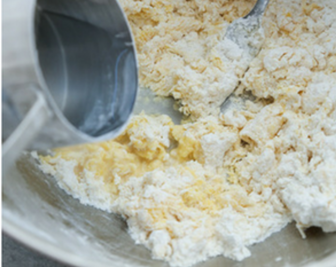 Schritt 1 Mehl, glutenfrei (235 g) in eine grosse Rührschüssel geben und an den Seiten hochdrücken, so dass in der Mitte eine Vertiefung entsteht. Eier (2) in die Vertiefung schlagen und mit einer Gabel verquirlen, wobei nach und nach immer mehr Mehl untergemischt wird. Wasser (120 ml) esslöffelweise hinzufügen, bis der Teig feucht ist und beginnt, zusammenzuhalten. Er sollte die Konsistenz von Spielteig haben, mit nur ein paar trockenen Krümeln.