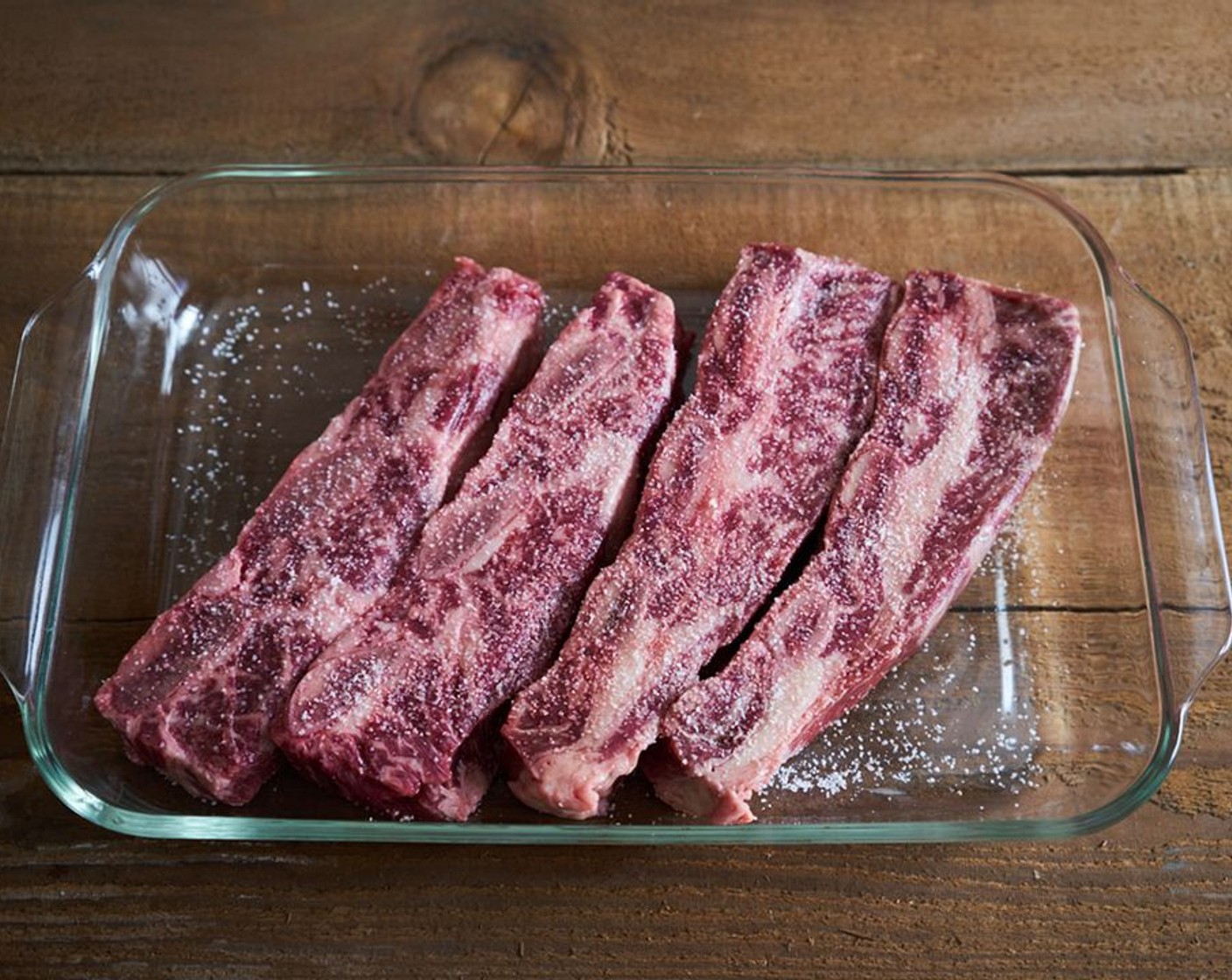 Schritt 8 Die Rinderrippchen (1.4 kg) in eine Glasauflaufform legen. Mit Salz würzen und bei Raumtemperatur mindestens 15 Minuten und bis zu zwei Stunden ruhen lassen.