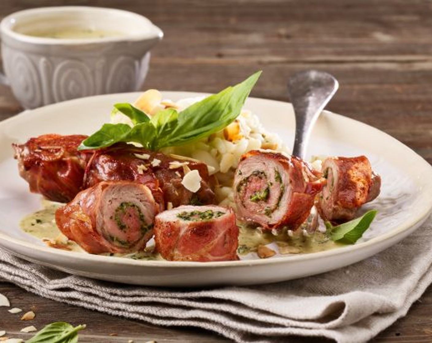 Schritt 5 Den Noilly Prat (3 1/3 Esslöffel) oder Weisswein zum Bratensatz geben und auf etwa 2 Esslöffel einkochen lassen. Dann den beiseitegestellten Pesto und dem Rahm (100 ml) beifügen, kräftig aufkochen, die Sauce wenn nötig nachwürzen und über die Kalbfleischrollen anrichten. Mit den beiseitegelegten Mandelblättchen sowie den Basilikumblättchen garnieren.