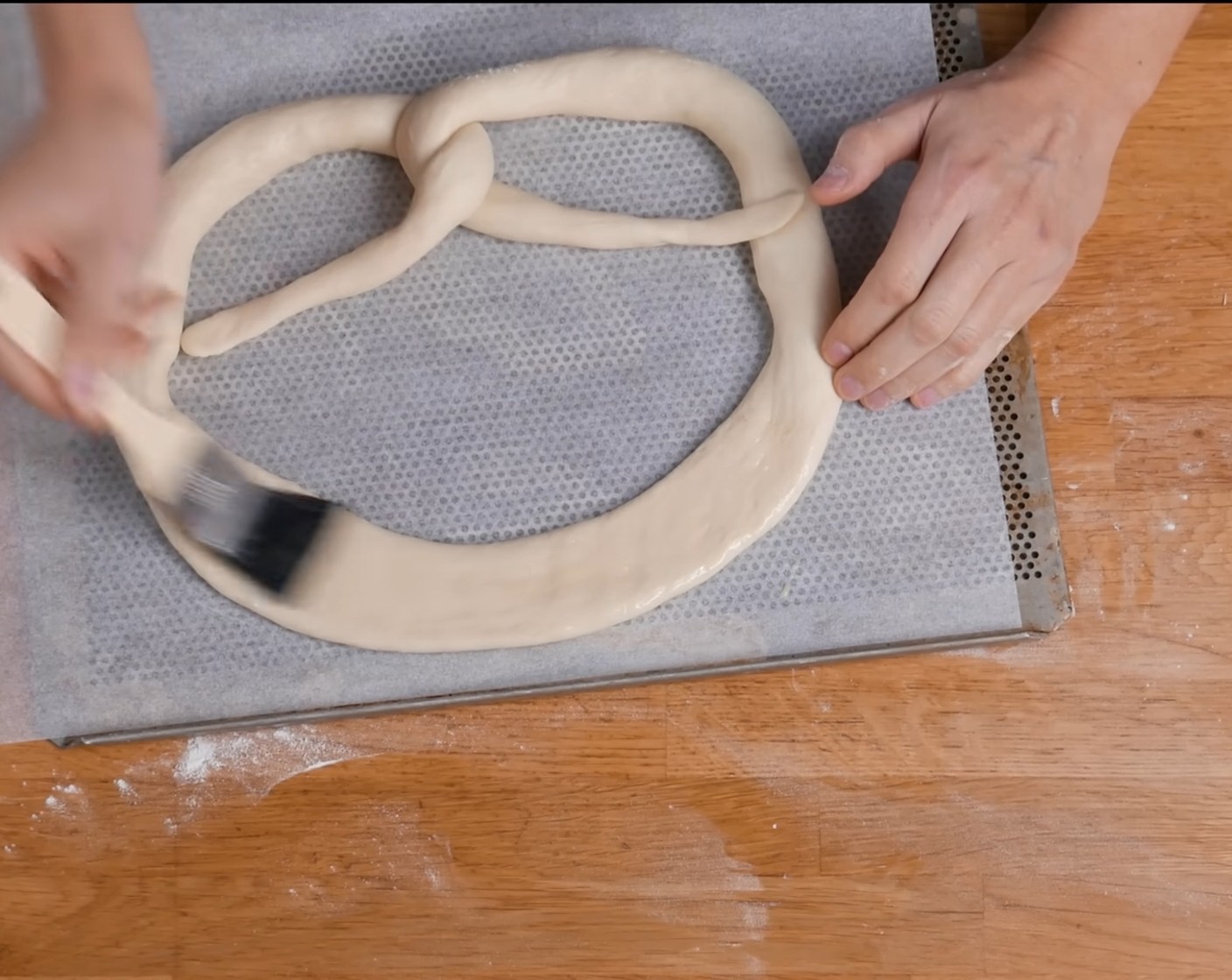 Schritt 14 Die obere Seite der Brezel etwas flachdrücken und mit verquirltem Ei (1) bestreichen.