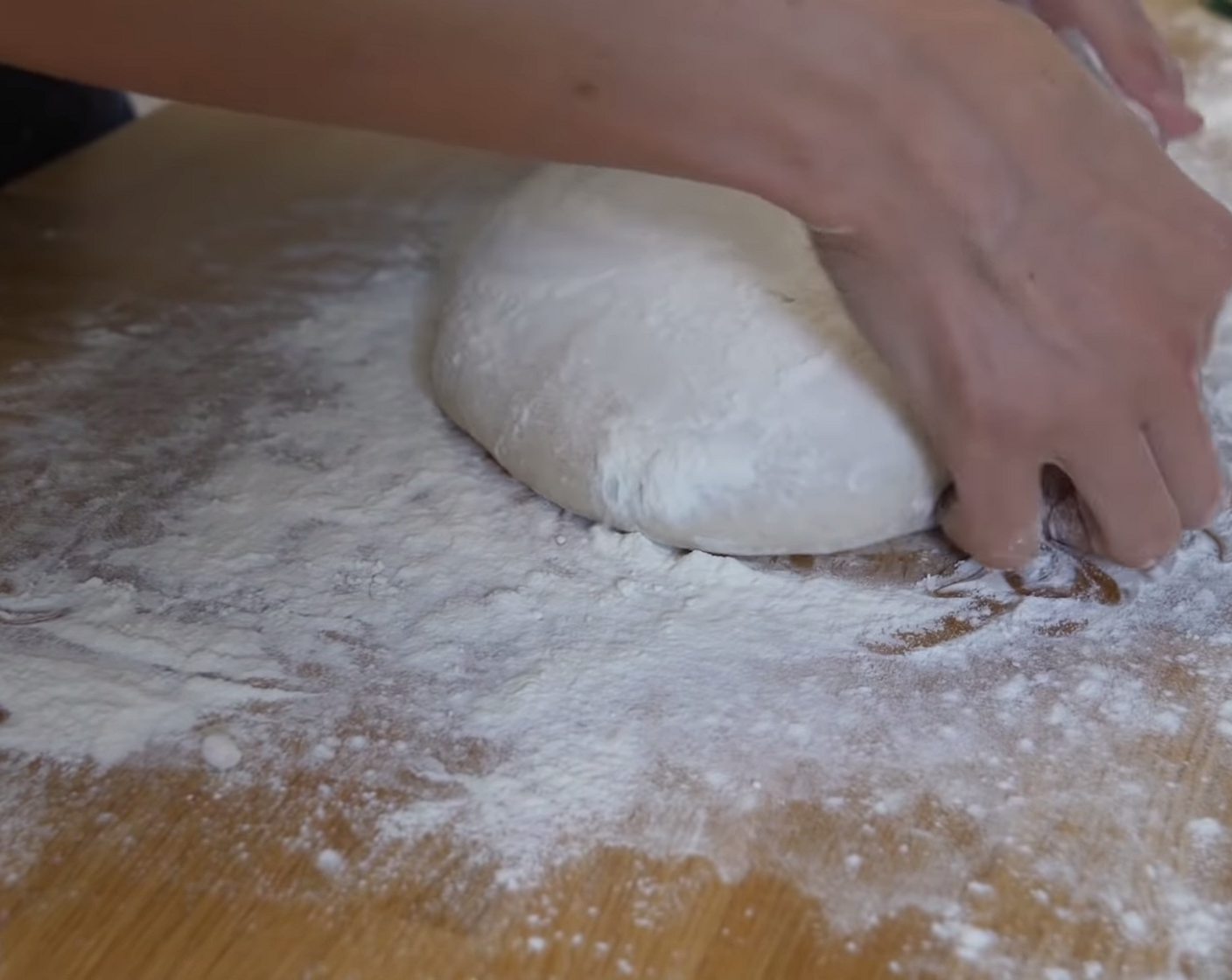 Schritt 6 Danach den Teig umdrehen (glatte Seite liegt nun oben), die Hände vasenförmig darumlegen und den Teig mit leichtem Druck auf der Tischplatte drehen, bis das Teigstück unten geschlossen ist. Hinweis: Damit sich die Teigkugel am unteren Ende gut verschliesst, sollte bei diesem Arbeitsschritt kein, bis nur ganz wenig Mehl verwendet werden.