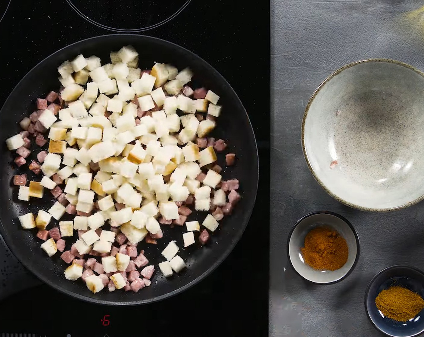 Schritt 3 Inzwischen Weissbrot (100 g) in kleine Würfelchen schneiden. In einer weiteren Pfanne Speckwürfel (100 g) im restlichen Olivenöl (1 EL) anbraten. Brotwürfelchen dazugeben und bei mittlerer Hitze rundum rösten. Mit scharfem Paprika (1/2 TL), süssem Paprika (1 Pr.), Salz (wenig) und Pfeffer (wenig) würzen.