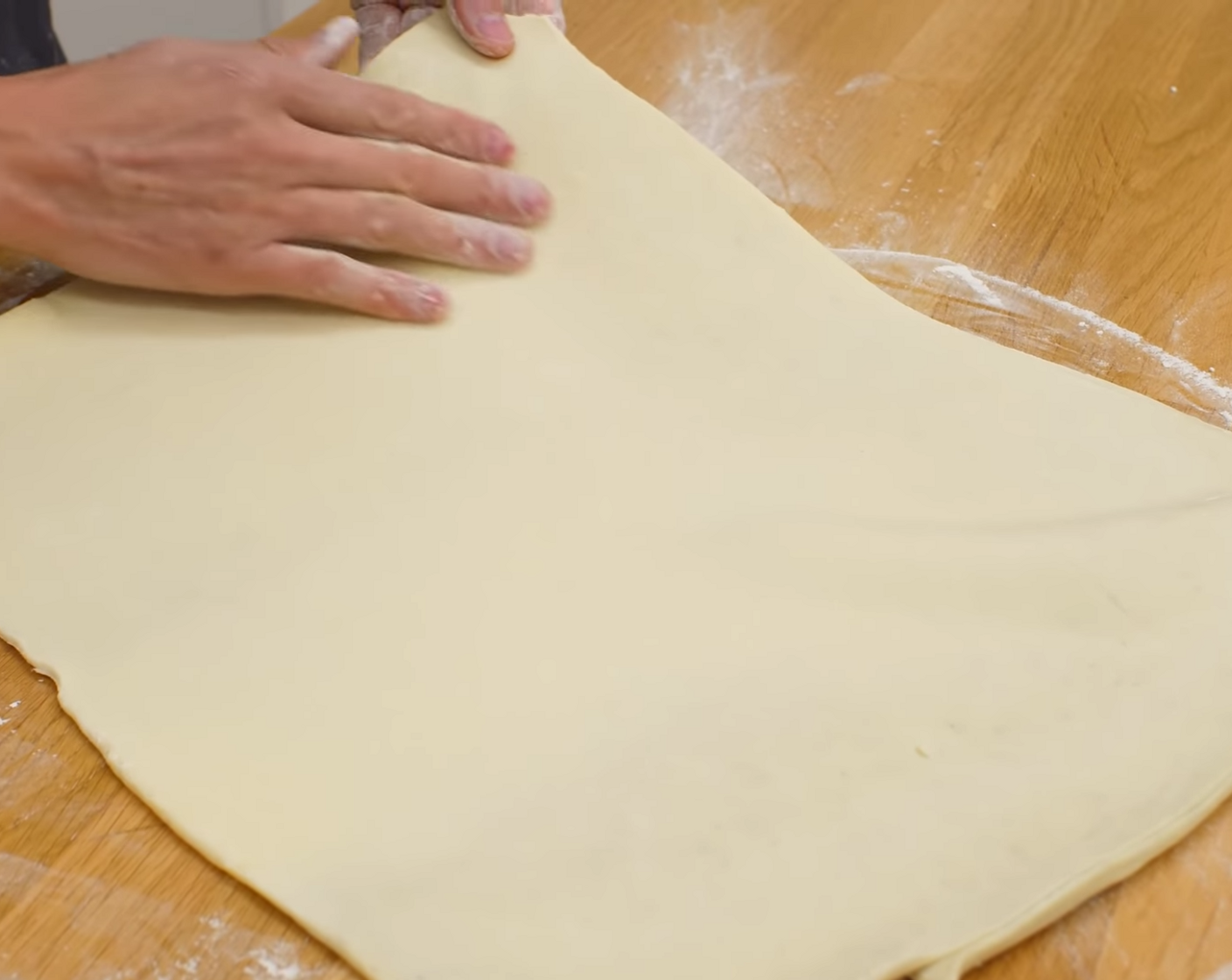 Schritt 9 Den gut gekühlten Blätterteig auf einer mit Mehl bestaubten Arbeitsfläche rechteckig ca. 2 mm dick ausrollen. Zwischendurch den Teig auf der Arbeitsfläche immer wieder leicht auflockern, damit er nicht an der Arbeitsfläche klebt.