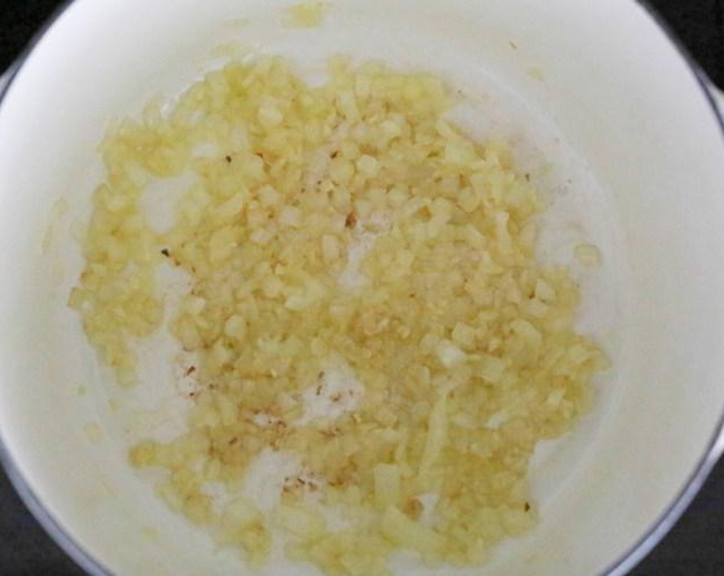 Schritt 1 Olivenöl (1 1/2 Esslöffel) in einem mittelgrossen Schmortopf oder einem Suppentopf mit schwerem Boden bei mittlerer Hitze erwärmen. Wenn das Öl heiss und glänzend ist, Zwiebeln (1/2), Knoblauch (4 Zehen) und Salz (1 Pr.) hinzufügen. Das Ganze für etwa 5 Minuten kochen, bis die Zwiebeln sehr weich und durchscheinend sind.