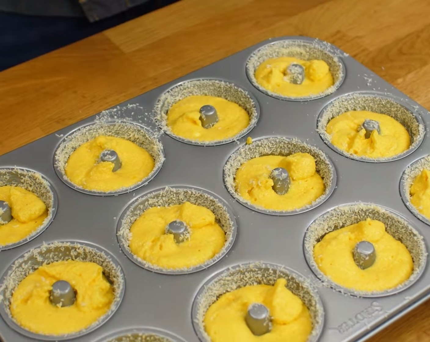 Schritt 8 Als nächstes die Masse in einen Spritzbeutel füllen und die Mulden des vorbereiteten Gugelhupf-Backbleches bis etwa 1 cm unter den Rand mit dem Teig füllen.