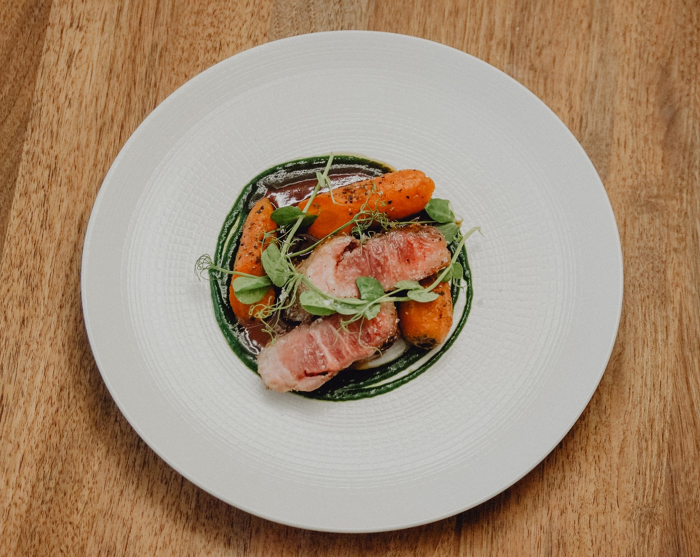 Schritt 8 Das Fleisch in 3 Stücke schneiden. Die Rucola-Creme kreisförmig auf den Teller verteilen. Dann das Fleisch mittig platzieren. Rundum die Karotten mit dem Jus verteilen und anschliessend mit den Sojasprosse (1 Handvoll) dekorieren.